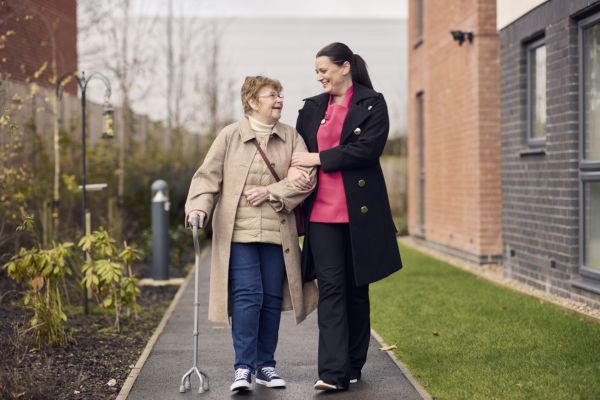 carer helping an elderly resident walk
